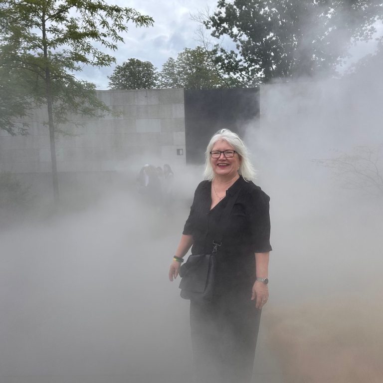 Martina Weber steht in einer nebeligen Landschaft. Symbol für Führungskräfte in Krisen